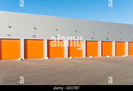 außen eine gewerbliche Lagerhalle mit orange Rolltore Stockfoto
