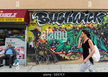 New York City, NY, USA, Amerikaner in Brooklyn, Bushwick Nachbarschaft, Frau Telefon nyc Öffentlichkeit, Wandern, Gespräch über Smartphone, Store Front Street Art, Ambiente öffentliche Kunst New york City bunt, Grafitti brooklyn Art 21. Jahrhundert Stockfoto