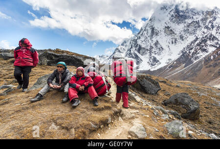 Träger mit schweren Last nach der Überquerung der Cho La Pass im Himalaya, gelegen in Solukhumbu 5.420 m (17.782 ft) über dem Meeresspiegel. Stockfoto