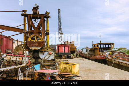 Verfallenen Maschinen und Eisen Flussschiffen links entlang des Ufers des Flusses Rumpf an einem hellen Sommertag zu rosten. Stockfoto