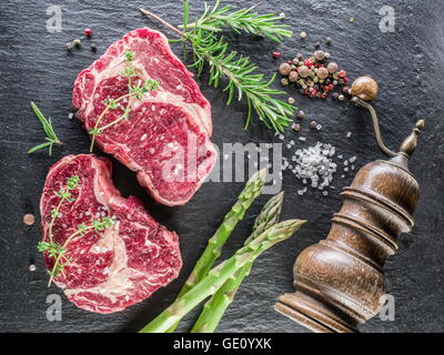 Rib-Eye Steak mit Gewürzen auf dem schwarzen Hintergrund. Stockfoto