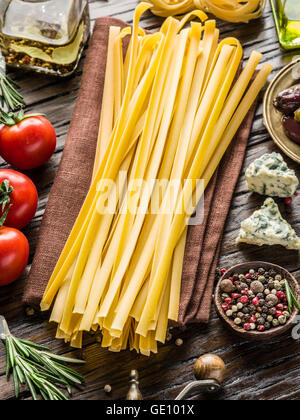 Pasta Zutaten. Cherry-Tomaten, Spaghetti Nudeln, Rosmarin und Gewürze auf dem Holztisch. Stockfoto