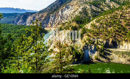 Lange Containerzüge nach dem Thompson River entlang steiler Klippen und durch Tunnel in den Fraser Canyon in British Columbia, Kanada Stockfoto