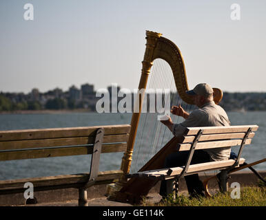 Musiker-Harfenistin Performer sitzen auf einer Bank am Meer in Vancouver, Kanada Stockfoto