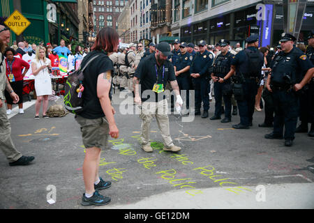 07212016 - Cleveland, Ohio, USA: Ein Demonstrant schreibt in Kreide, "entwaffnen die Polizei' nur einen Mann behauptet, zu sein eine Kriegsveteran gießen Wasser auf die Nachricht, es am Eingang der Republican National Convention, zu zensieren" am letzten Tag der Republican National Convention 2016 in der Innenstadt von Cleveland. (Jeremy Hogan) Stockfoto