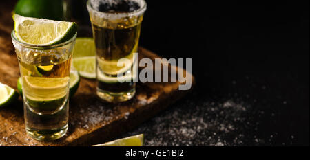 Zwei Gold Tequila Shots mit Kalk, Textfreiraum auf rechten Seite. Gold mexikanische Tequila. Alkohol trinken. Stockfoto