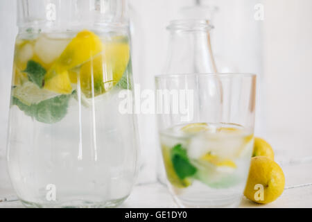 Glas und Krug Wasser mit frischer Zitrone, Limette, Minze und Eis-Würfel Stockfoto