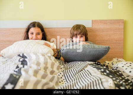 Jungen und Mädchen sitzen im Bett versteckt unter abdeckt Stockfoto