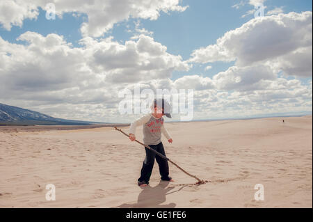 Junge schreiben in Sand mit Stock, Grand Sand Dunes National Park, Colorado, USA Stockfoto