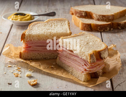 Ein geräuchertes Fleisch Sandwich auf einem Holztisch mit Senf. Stockfoto