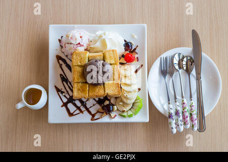 Honig-Toast Schlagsahne mit Schokolade Eis und Löffel Gabel Messer auf Holz Hintergrund Stockfoto