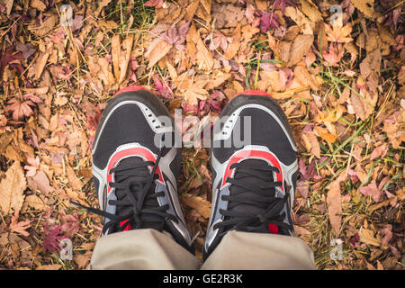 Füße Mann Stand im Herbst Blätter im Freien mit Herbst Saison Natur auf Hintergrund Stockfoto