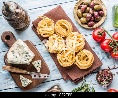 Pasta Zutaten. Cherry-Tomaten, Spaghetti Nudeln, Rosmarin und Gewürze auf dem Holztisch. Stockfoto