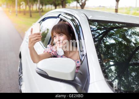 Frau Hand mit Smartphone auf Fenster weiße Auto Stockfoto