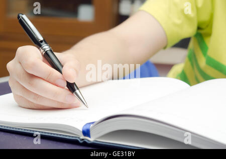 Write-Aktivität (eine Mädchen Hand hält einen Stift und schreiben auf ein Buch) Stockfoto