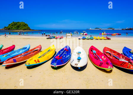 Surfer am schönen Strand und das Meer mit Segelboot und Wolken in Ferne Stockfoto