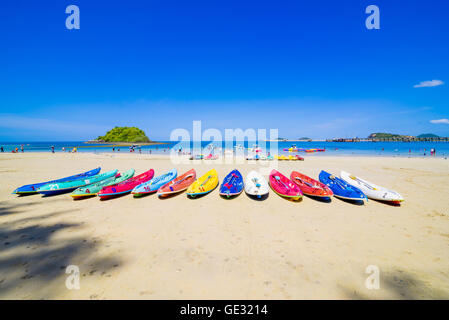 Surfer am schönen Strand und das Meer mit Segelboot und Wolken in Ferne Stockfoto