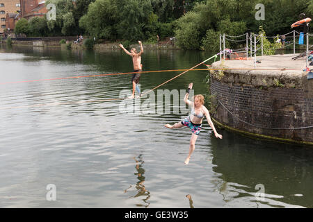 Shadwell, London. VEREINIGTES KÖNIGREICH. 23. Juli 2016. Menschen, die Slacklinen bei heißen, sonnigen Wetter in Shadwell Basin in Ost-London heute Nachmittag genießen. Slacklinen ist der Sport der balancieren auf einem Gurtband, das hoch über dem Boden befestigt, aber nicht zu straff gespannt. Menschen wurden gewarnt, nicht zum Schwimmen in Shadwell Basin, nachdem ein Mann ertrank und starb diese Woche. Bildnachweis: Vickie Flores/Alamy Live-Nachrichten Stockfoto