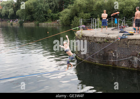 Shadwell, London. VEREINIGTES KÖNIGREICH. 23. Juli 2016. Menschen, die Slacklinen bei heißen, sonnigen Wetter in Shadwell Basin in Ost-London heute Nachmittag genießen. Slacklinen ist der Sport der balancieren auf einem Gurtband, das hoch über dem Boden befestigt, aber nicht zu straff gespannt. Menschen wurden gewarnt, nicht zum Schwimmen in Shadwell Basin, nachdem ein Mann ertrank und starb diese Woche. Bildnachweis: Vickie Flores/Alamy Live-Nachrichten Stockfoto