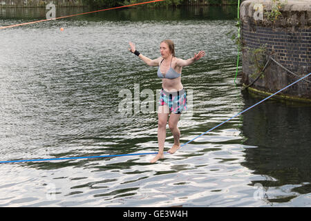 Shadwell, London. VEREINIGTES KÖNIGREICH. 23. Juli 2016. Menschen, die Slacklinen bei heißen, sonnigen Wetter in Shadwell Basin in Ost-London heute Nachmittag genießen. Slacklinen ist der Sport der balancieren auf einem Gurtband, das hoch über dem Boden befestigt, aber nicht zu straff gespannt. Menschen wurden gewarnt, nicht zum Schwimmen in Shadwell Basin, nachdem ein Mann ertrank und starb diese Woche. Bildnachweis: Vickie Flores/Alamy Live-Nachrichten Stockfoto