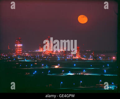 Ein Vollmond erleuchtet den Himmel über der Missile Row auf der Cape Canaveral Air Force Station, wobei die Starthallen leuchten und sich entlang der Küste erstrecken. Stockfoto