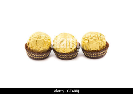 Süßen Schokokugeln mit Mandel eingehüllt in Goldfolie Papier auf weißem Hintergrund Stockfoto