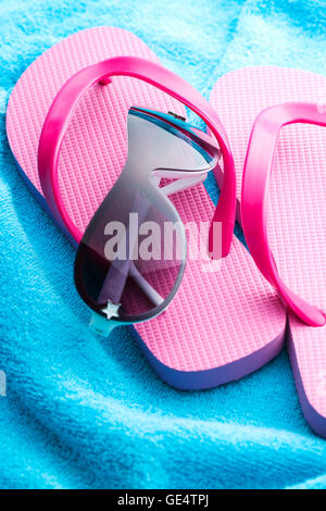 Flip Flops und Sonnenbrillen auf blaues Handtuch. Stockfoto