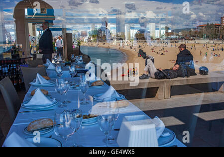 Spiegelungen auf dem Glas eines Restaurants vor Nova Icaria Beach, Port Olimpic, Barcelona, Spanien Stockfoto