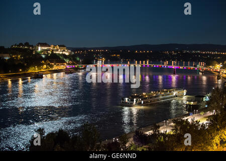 Festung Petrovaradin und "Rainbow Bridge" über die Donau zwischen Novi Sad und Petrovaradin im Mondlicht mit Schiff andocken Stockfoto