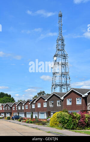 BT-Funkmast und Satellitenschüsseln über sich wiederholende Fassade von Wohnungen in der Vorstadtstraße Kelvedon Hatch Brentwood Essex England Stockfoto