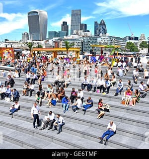 Southwark Büroangestellte nehmen heiße sonnige Mittagspause im Mehr London Scoop Amphitheater am Fluss mit City of London Skyline Über England hinaus Stockfoto