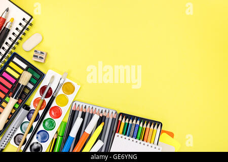 gelbe Schreibtisch mit bunten Schreibwaren und Büromaterial für Bildungsprozess Stockfoto