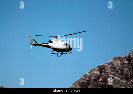 Ein Hubschrauber auf der Flucht vor einem blauen Himmel in Hügeln. Stockfoto