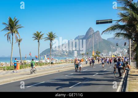 Aktive Einwohner und Touristen schlendern Sie in der Nähe von Posto 9 am Strand von Ipanema, an einem autofreien Sonntag Morgen. Rio 2016 beginnt bald. Stockfoto