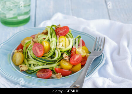 Zucchini-Nudeln mit Tomaten und Walnüssen in Olivenöl geschwenkt Stockfoto