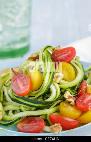 Zucchini-Nudeln mit Tomaten und Walnüssen in Olivenöl geschwenkt Stockfoto