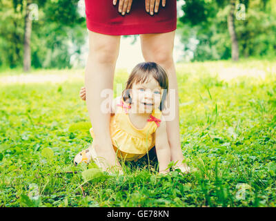 einjährigen Babymädchen zwischen den Beinen der Mutter im freien Stockfoto