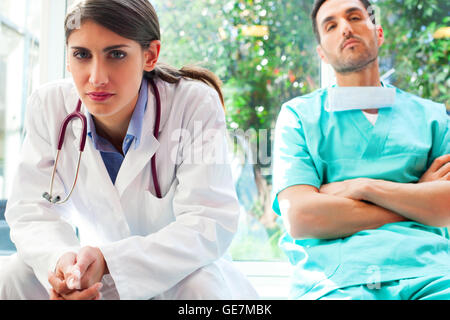 Porträt von Ernst Ärztin mit Kollegen im Krankenhaus. Junge Mediziner sind in Uniformen. Sie sitzen in c Stockfoto