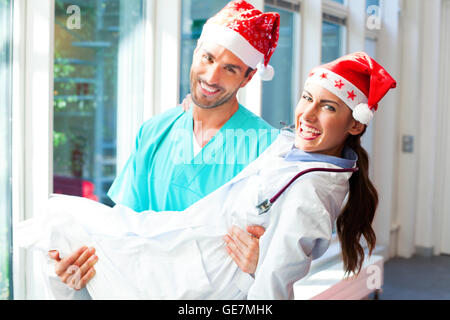 Ein Foto von männlichen Arzt Ärztin tragen. Glückliche junge Mediziner tragen Santa Hüte. Sie sind in Uniformen, die ich Stockfoto