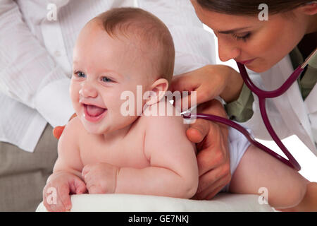 Ein Foto von weiblichen Kinderarzt untersuchen Babyjungen Besitz Vater Arzt des Patienten wieder mit Stethoskop Toddl anhören Stockfoto