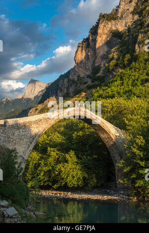 Die alte Steinbrücke über den Fluss Aoos bei Konitsa mit Mount Tymfi in den Hintergrund, Epirus, Nordgriechenland. Stockfoto