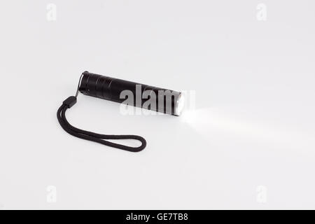 kleine Taschenlampe arbeiten auf einem weißen Hintergrund mit einem Strahl von Licht Stockfoto