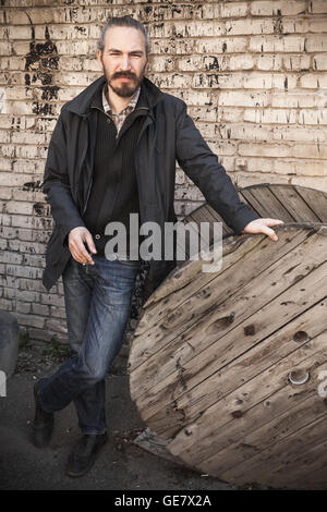 Im freien vertikalen Porträt der jungen asiatischen Mann in schwarz über grau urban Grunge Brick Wand Hintergrund Stockfoto