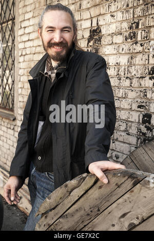 Outdoor Portrait jungen asiatischen Mann in schwarz auf grau urban Grunge Brick Wand Hintergrund lächelt Stockfoto