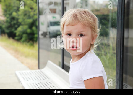 Niedliche kaukasischen blonde Babymädchen wartet auf eine Bushaltestelle Stockfoto