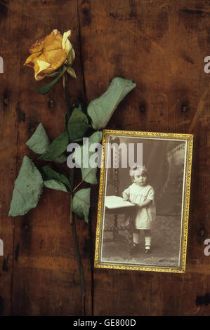 Umrahmt von Sepia Foto von viktorianischen Kleinkind Stuhl mit getrocknete gelbe rose liegend neben dem Holztisch steht Stockfoto