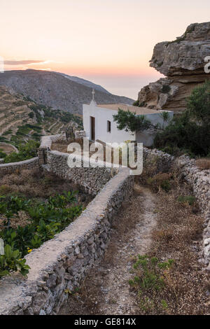 Sonnenuntergang über der kleinen weißen Saint Vasilios Kirche am Stadtrand von Chora Insel Folegandros, Griechenland Stockfoto