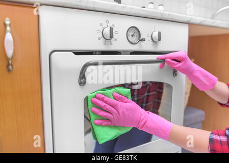 Weibliche Hände in Handschuhen gewaschen Ofen außerhalb. Reinigung der Küche. Stockfoto