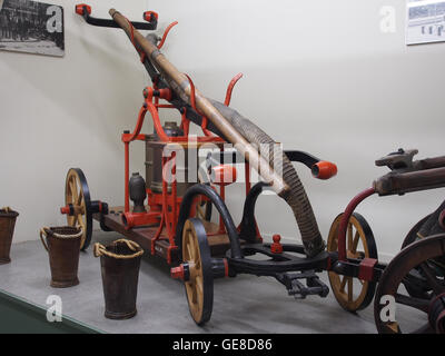 Ein Bild eines alten Feuerwehrfahrzeugs (Oude blusspuit), das das historische Design und die Struktur der Löschausrüstung erfasst. Dieses Vintage-Foto zeigt die technologischen Fortschritte bei Feuerlöschwerkzeugen aus einer früheren Ära. Stockfoto