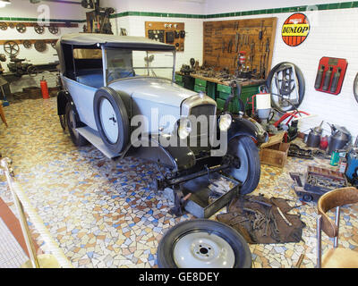 Dieses Foto zeigt ein Peugeot-Fahrzeug in einer Werkstatt, das die Kfz-Handwerkskunst und das Design von Autos aus dem frühen 20. Jahrhundert hervorhebt. Das Bild zeigt die komplizierte Arbeit der Mechaniker bei der Wartung von Oldtimern. Stockfoto